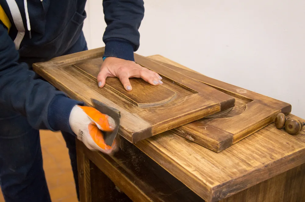 Alumna del taller lijando minuciosamente un mueble de madera antiguo para su restauración.